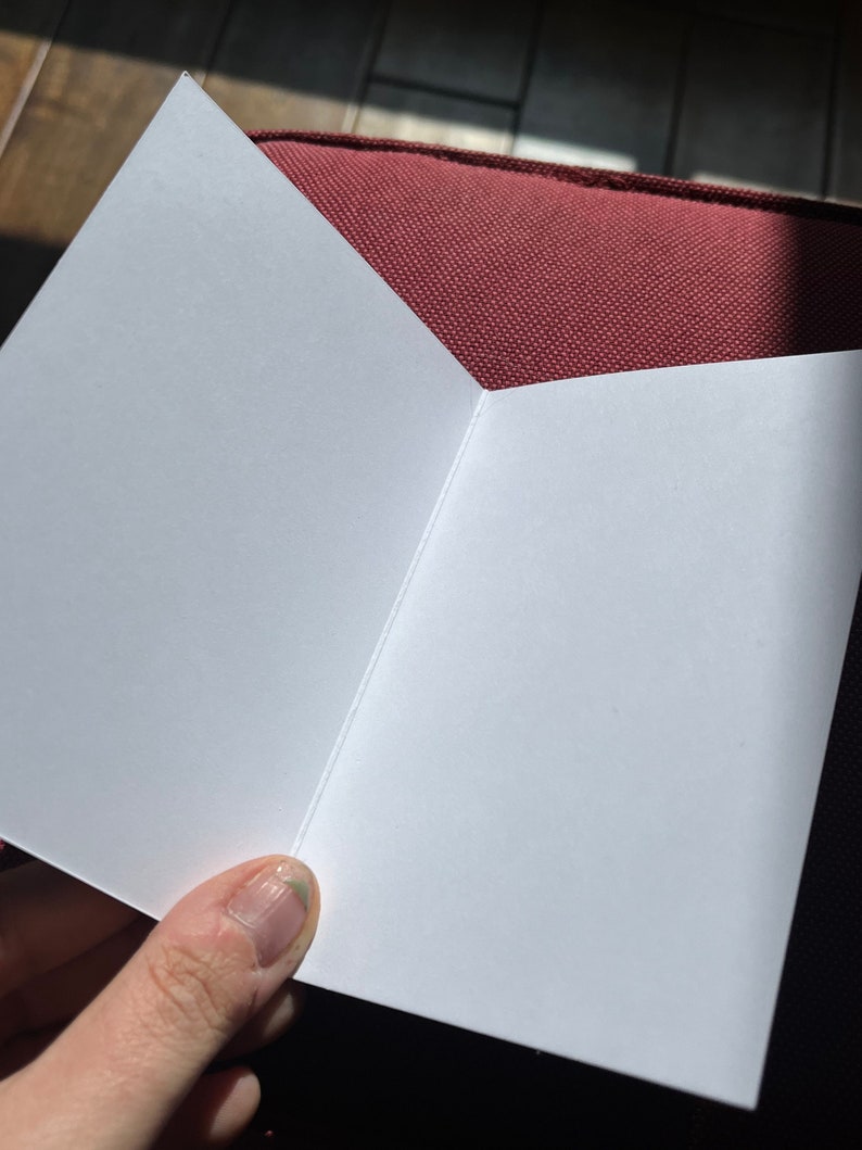 May include: A blank white card folded in half, with a slight crease down the centre.