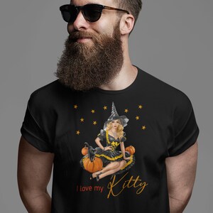 May include: Black t-shirt with a graphic of a witch sitting on pumpkins with a black cat. The text "I love my Kitty" is printed on the shirt.