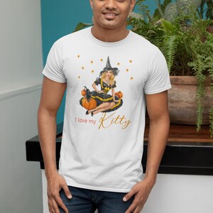 May include: White t-shirt with a graphic of a witch sitting on pumpkins with the text "I love my Kitty" in gold lettering.