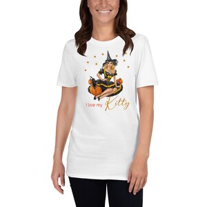 May include: White t-shirt with a black and yellow witch illustration sitting on pumpkins. The text "I love my Kitty" is printed below the illustration.