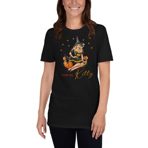 May include: Black t-shirt with a graphic of a woman dressed as a witch sitting on pumpkins. The text "I love my Kitty" is printed below the graphic.