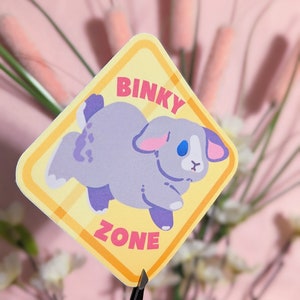 May include: A yellow diamond-shaped sticker with a cartoon bunny rabbit in the center. The sticker says "Binky Zone" in pink and white letters.