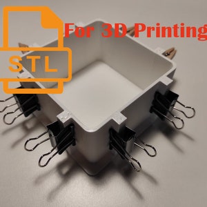 Puede incluir: Una caja blanca impresa en 3D con una abertura cuadrada. La caja se mantiene unida con clips de carpeta. El texto "For 3D Printing" y "STL" es visible en la imagen.