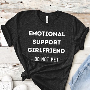May include: A dark gray t-shirt with the text "Emotional Support Girlfriend - Do Not Pet -" in white.