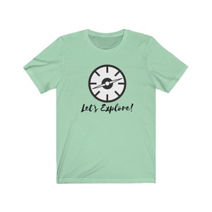May include: A light green t-shirt with a black compass graphic and the text "Let's Explore!" printed on the front.