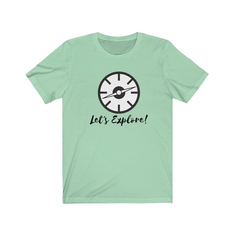 May include: A light green t-shirt with a black compass graphic and the text "Let's Explore!" printed on the front.