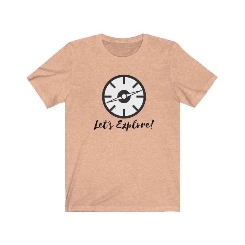 May include: A light peach colored t-shirt with a black compass graphic and the text "Let's Explore!" printed on the front.