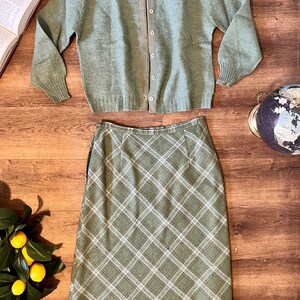 Puede incluir: Un c&aacute;rdigan de punto verde con cierre de botones en la espalda, combinado con una falda de cuadros verdes.