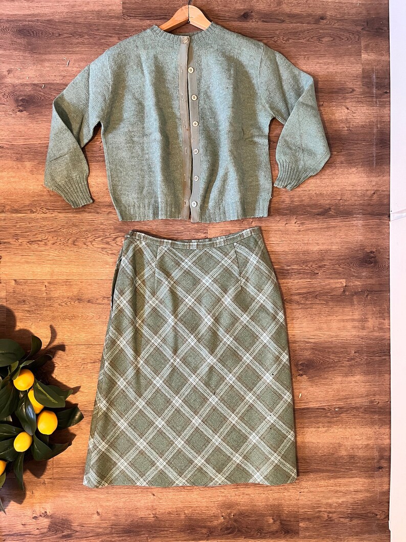 Puede incluir: Un c&aacute;rdigan de punto verde con cierre de botones en la espalda, combinado con una falda de cuadros verdes.