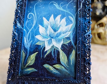 May include: A rectangular painting of a white lotus flower set against a dark blue background with swirling light blue vines, enclosed in an ornate, dark blue, textured frame with intricate scrollwork and beaded detailing along the edges.