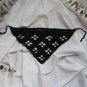 May include: Black crocheted triangle scarf with a floral pattern.
