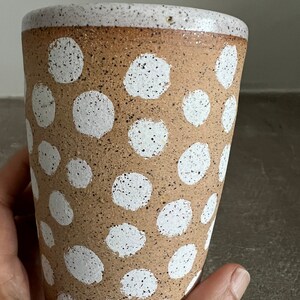 May include: A brown ceramic mug with a white speckled glaze and a white polka dot pattern.