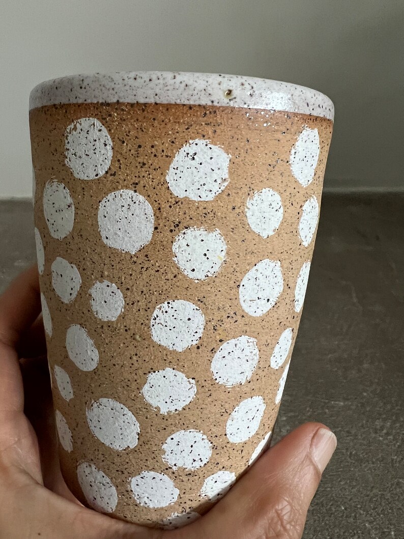 May include: A brown ceramic mug with a white speckled glaze and a white polka dot pattern.