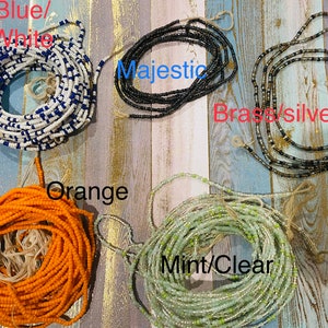 May include: Assortment of colourful beaded waist beads, including blue and white, black, brass, silver, orange, and mint green.