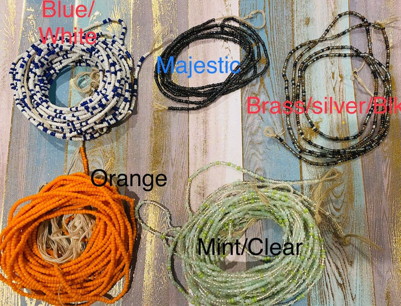May include: Assortment of colourful beaded waist beads, including blue and white, black, brass, silver, orange, and mint green.
