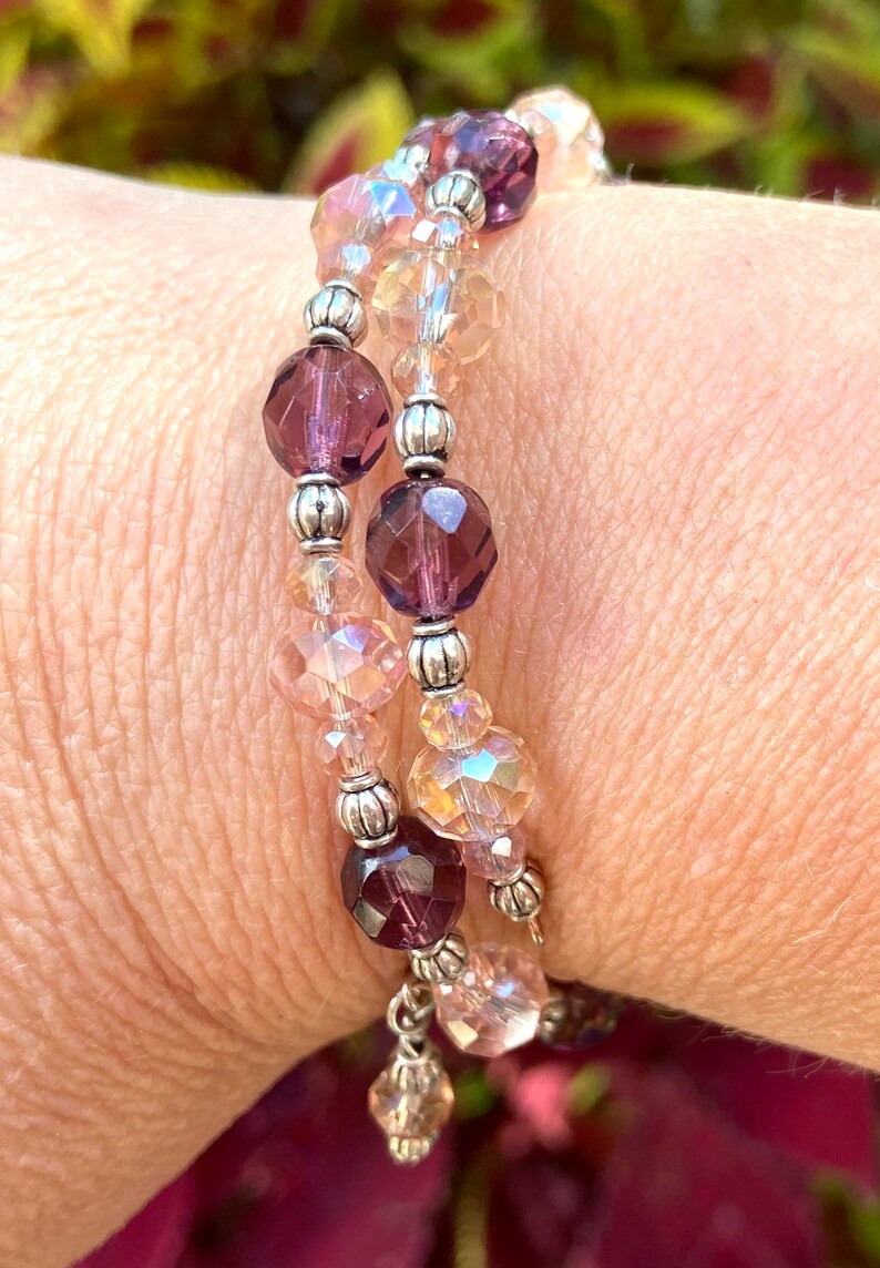 May include: A double-strand bracelet with silver beads and faceted glass beads in shades of pink and purple.