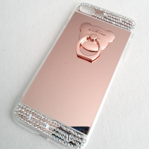 Pode incluir: Capa de telefone espelhada em ouro rosa com uma borda transparente e brilhante e um suporte de anel em forma de urso em ouro rosa com o texto "NEWLOVE BEAR STAND".