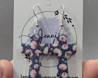 May include: A pair of sterling silver earrings featuring a floral cross design. The cross is made of blue and white floral patterned acrylic. The earrings are displayed on a white card with the text "Jenniferlynncrafts.com" and "Sterling Silver".