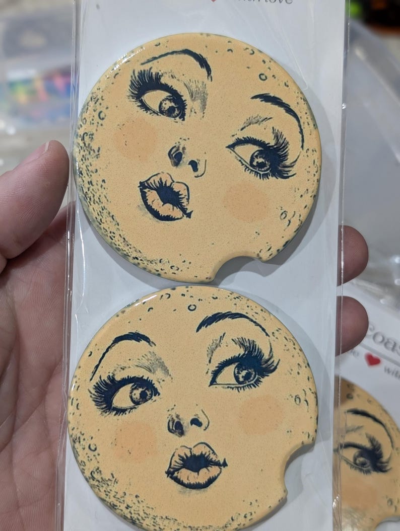 Puede incluir: Dos posavasos redondos para coche con dise&ntilde;o de cara. Los posavasos tienen un fondo de color beige claro con un dise&ntilde;o de cara en negro y melocot&oacute;n. La cara tiene pesta&ntilde;as largas, una boca de beso y mejillas rosadas. Los posavasos est&aacute;n empaquetados en pl&aacute;stico transparente.