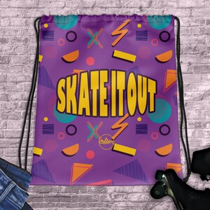 Puede incluir: Bolsa de cordón morado con un patrón geométrico en amarillo, naranja y azul. La bolsa tiene el texto "Skate It Out" en letras amarillas.