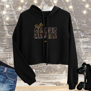 May include: Black cropped hoodie with a gold and red word cloud design that says "Roller Skate" with words like "wheels", "stride", "music", and "rhythm".