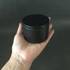 a person holding a black container in their hand