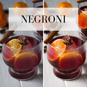 Puede incluir: Primer plano de dos c&oacute;cteles Negroni con rodajas de naranja, an&iacute;s estrellado y palitos de canela. Los c&oacute;cteles est&aacute;n en vasos transparentes y est&aacute;n sobre una superficie de madera blanca.