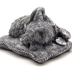 May include: Silver pet memorial figurine of a sleeping dog on a pillow with a heart-shaped tag that reads "Rosie 1991-2017".
