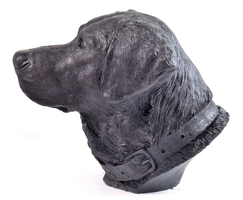 May include: Black Labrador Retriever dog head sculpture. The sculpture is made of a dark gray material and has a realistic appearance. The dog is wearing a black leather collar.