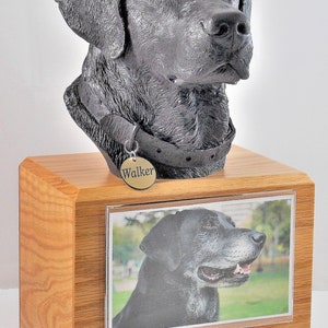 Puede incluir: Una urna de madera para mascotas con un busto de perro negro en la parte superior. La urna tiene una foto del perro y una placa que dice "Walker You Left Paw Prints On Our Hearts April 15, 2009 - June 21, 2018".