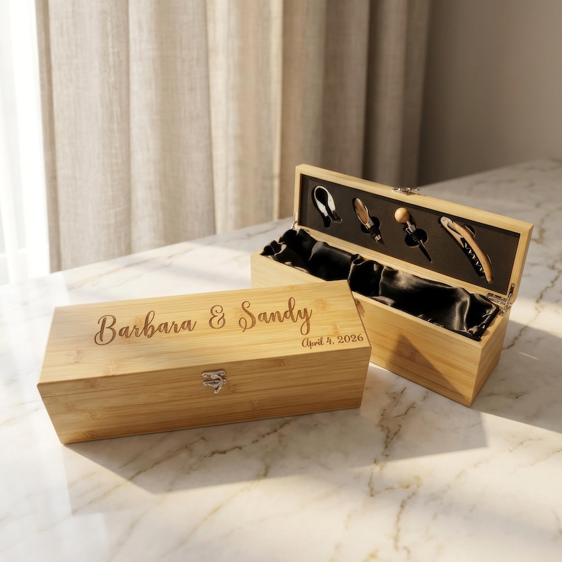 May include: Two bamboo wine boxes, one closed and one open, displaying wine tools. The closed box is engraved with "Barbara & Sandy" and "April 4, 2026." The open box reveals a black satin interior and various wine accessories.