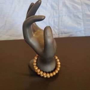 Puede incluir: Un brazalete de cuentas marrones con un acabado brillante.