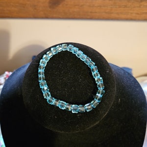 Puede incluir: Un brazalete azul claro hecho de cuentas cuadradas.