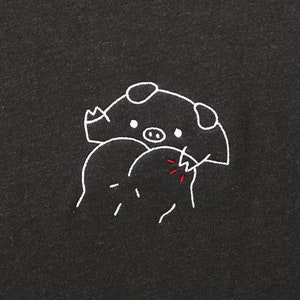 May include: A black t-shirt with a white embroidered design of a pig biting its own tail.