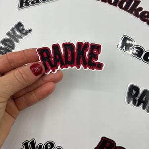 May include: A collection of stickers with the word "Radke" in different styles. One sticker features the word in a dripping, black and red font.