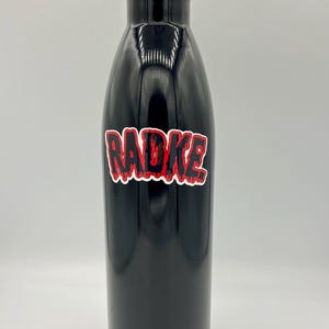 May include: Black stainless steel water bottle with a red and black "RADKE" sticker.