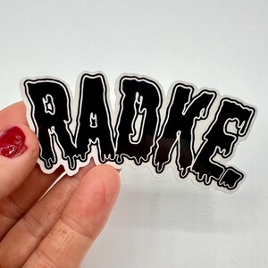 May include: Black and white sticker with the word "RADKE" in dripping letters.