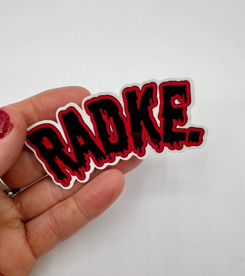 May include: A black and red sticker with the word "RADKE" written in a dripping, gothic font.