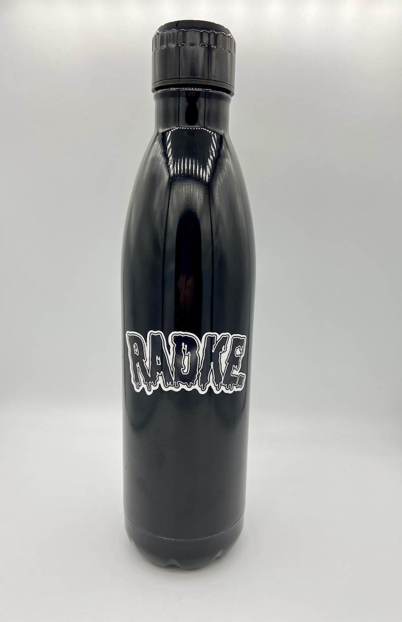 May include: Black stainless steel water bottle with a white sticker that says "RADKE" in dripping letters.