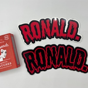 May include: Two stickers with the word "RONALD" in dripping red and black letters on a white background.