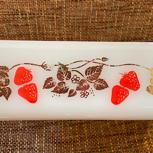 Op de afbeelding: Een rechthoekige witte melkglazen broodvorm met een decoratief patroon van felrode aardbeien en bruine bladranken. Het ontwerp is gecentreerd op de zijkant van de schaal en toont een botanisch motief met goudkleurige accenten op de bladeren.