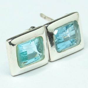 May include: A pair of silver earrings with square blue topaz gemstones.