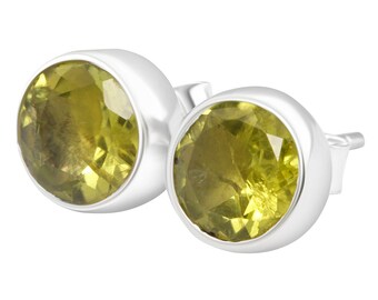 Puede incluir: Un par de pendientes de plata con piedras preciosas redondas, facetadas y verdes.