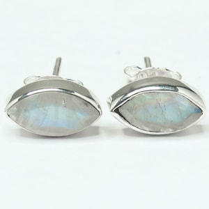 May include: A pair of silver earrings with oval-shaped moonstone gemstones. The earrings have a simple design and are a classic style.