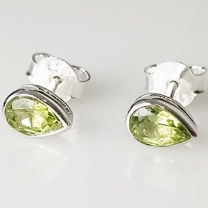 May include: A pair of silver stud earrings with pear-shaped green gemstones.