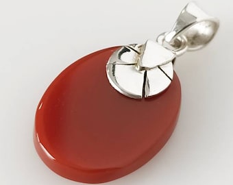 Puede incluir: Un colgante ovalado rojo con un diseño de filigrana plateada. El colgante está hecho de coral y plata.