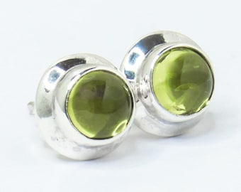 Puede incluir: Un par de pendientes de plata con detalles de piedras preciosas verdes.
