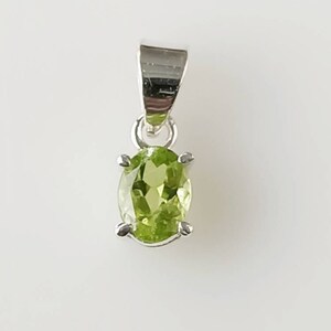 May include: A silver pendant with a green oval gemstone.