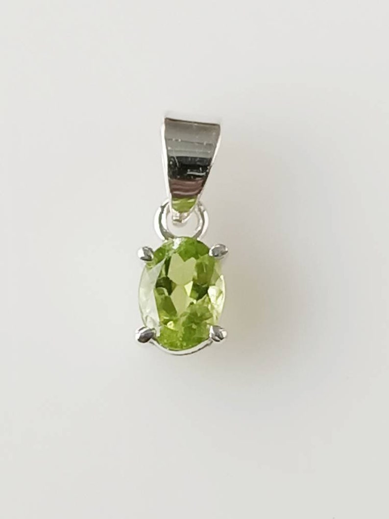 May include: A silver pendant with a green oval gemstone.