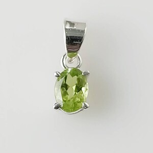 May include: A silver pendant with a green oval gemstone.